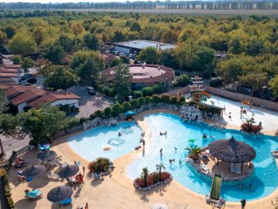 Piscina all'aperto con bungalow e vegetazione circostante.