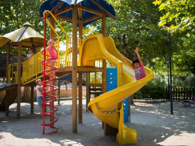 Bambini giocano su uno scivolo giallo al parco.