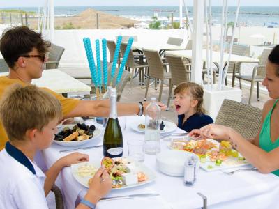 Famiglia pranza all'aperto vicino al mare, con cibo e bevande.