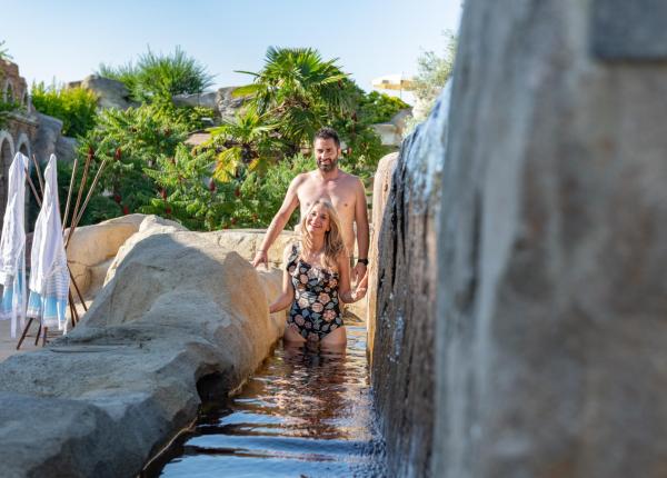 Un uomo in piedi in una piscina accanto a una grande roccia.