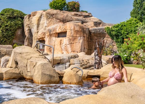 Una donna in bikini rosa seduta in una piscina rocciosa.