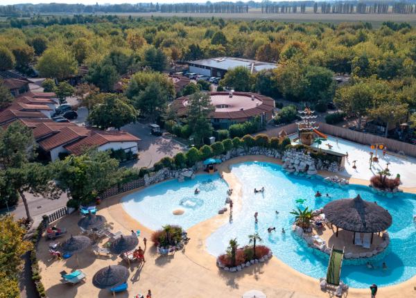 Piscina all'aperto con bungalow e vegetazione circostante.